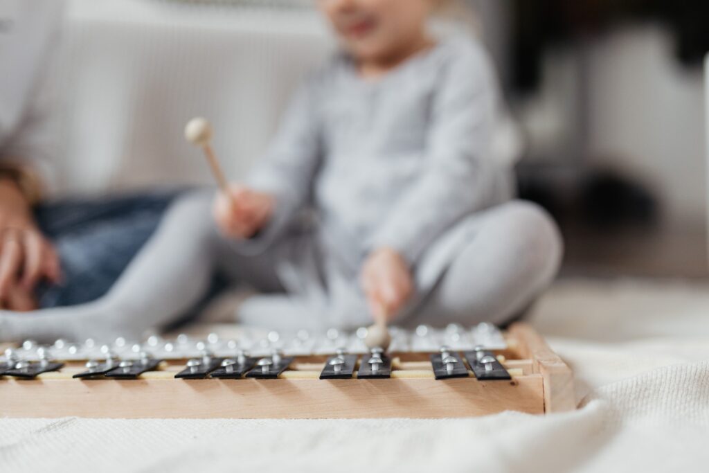A young child playing a xylophone on a soft blanket indoors, showcasing musical exploration.